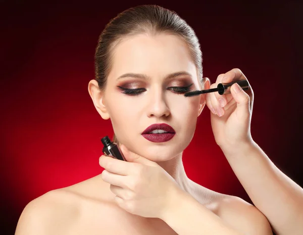 Artiste visage professionnel appliquant le maquillage sur le visage de la femme sur fond sombre — Photo