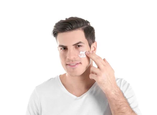 Bonito homem aplicando creme facial no fundo branco — Fotografia de Stock