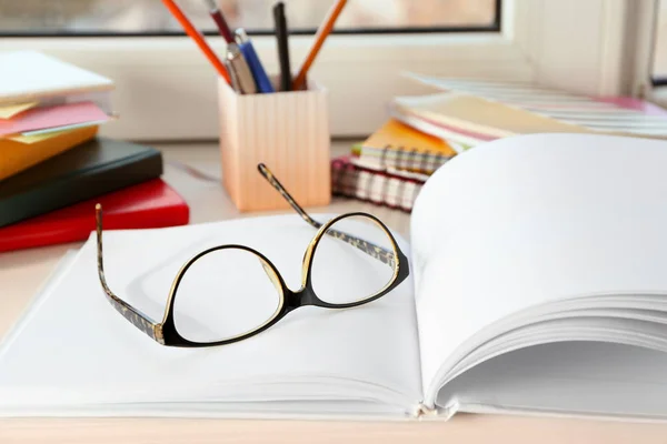 Glasses and notebook on windowsill indoors. Preparation for exam — Stock Photo, Image