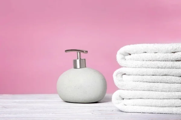 Asciugamani puliti e bottiglia di sapone in tavola — Foto Stock