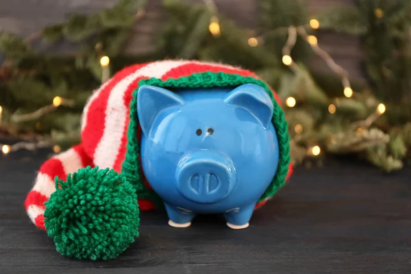 Piggy bank with striped hat and blurred Christmas lights on background — Stock Photo, Image