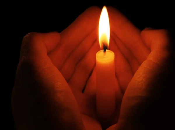 Молодая женщина держит горящую свечу в темноте — стоковое фото