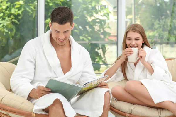 Unga älskande par i badrockar avkopplande inomhus — Stockfoto