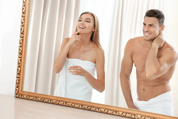 Joven pareja amorosa mirando en el espejo en la habitación de hotel —  Fotos de Stock
