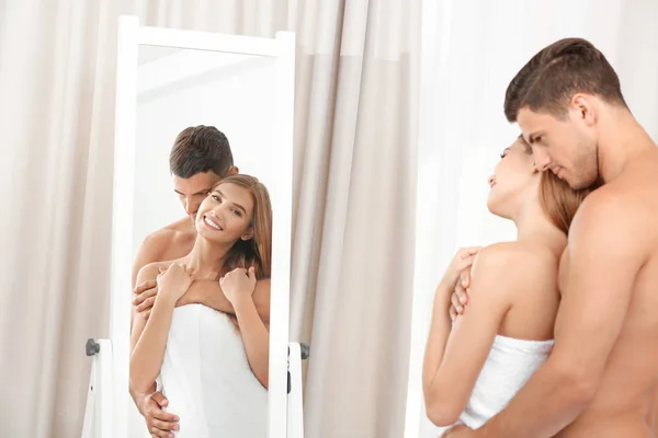 Jovem casal amoroso olhando no espelho no quarto de hotel — Fotografia de Stock