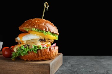 Siyah arka plan karşı tablo kızarmış yumurta ile lezzetli burger