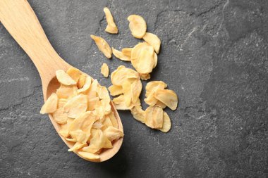 Tahta kaşıkla kuru sarımsak gevreği gri arka plan üzerinde