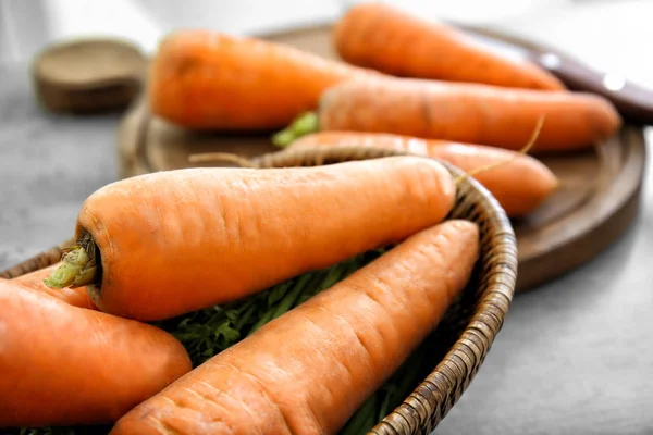 Rieten kom met verse wortelen op tafel, close-up — Stockfoto