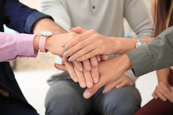 Unga medarbetare att sätta händerna ihop som symbol för enighet, närbild — Stockfoto