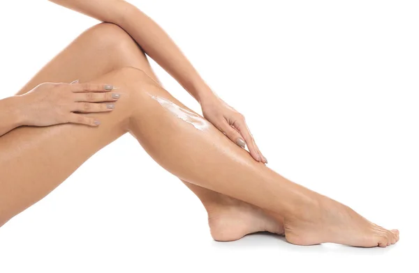 Woman applying body cream on her leg against white background, closeup — Stock Photo, Image