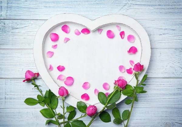 Roses and tray with petals on wooden background — Stock Photo, Image