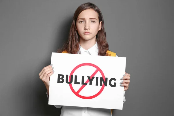 Genç kız işareti çapraz kelime ile "Bullying" gri arka plan üzerinde tutarak. — Stok fotoğraf