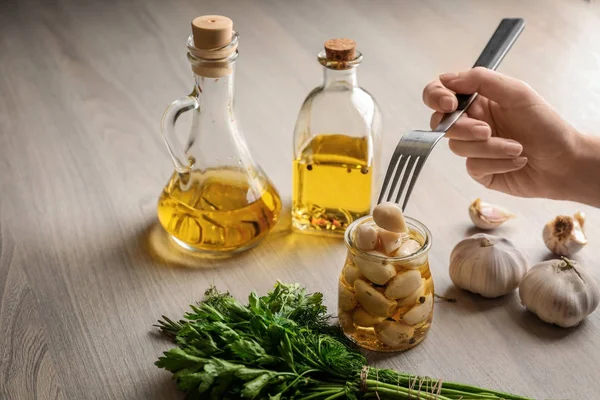 Woman trying preserved garlic on table, closeup — Stock Photo, Image