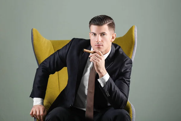 Mannen i elegant kostym med cigarr på grå bakgrund — Stockfoto