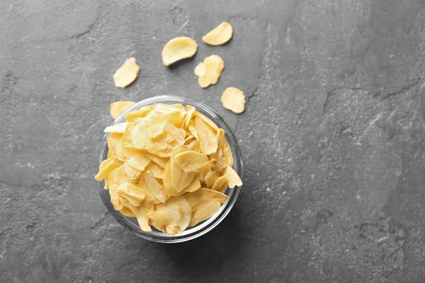 Glass bowl with dried garlic flakes on grey background — Stock Photo, Image