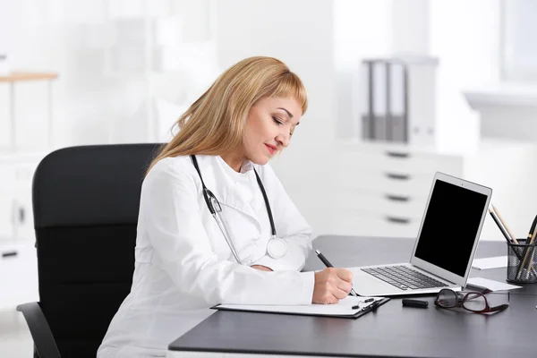 Médico femenino rellenando formulario de solicitud en sala de consulta —  Fotos de Stock