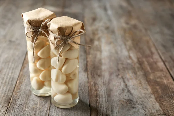 Preserved garlic in glass jars on wooden background — Stock Photo, Image