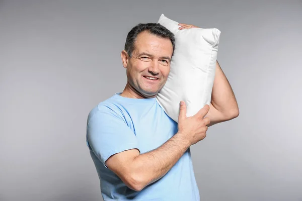 Зрелый мужчина с белой подушкой на сером фоне — стоковое фото