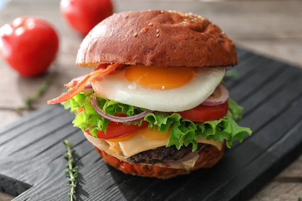 Вкусный бургер с яичницей на столе — стоковое фото