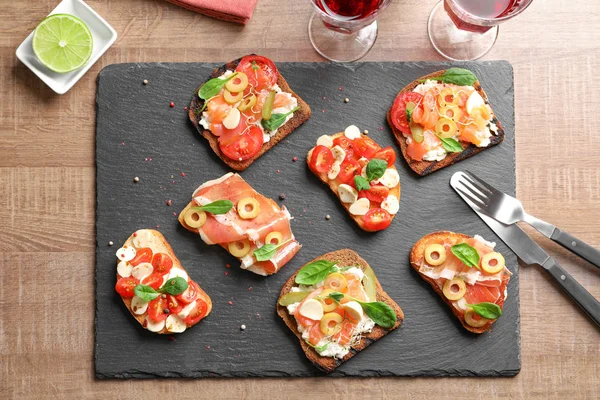 Slate plate with tasty bruschettas on table — Stock Photo, Image