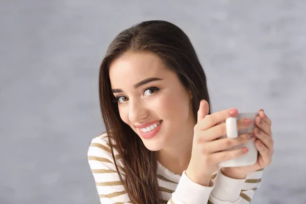 Красивая улыбающаяся женщина с чашкой кофе на сером фоне — стоковое фото