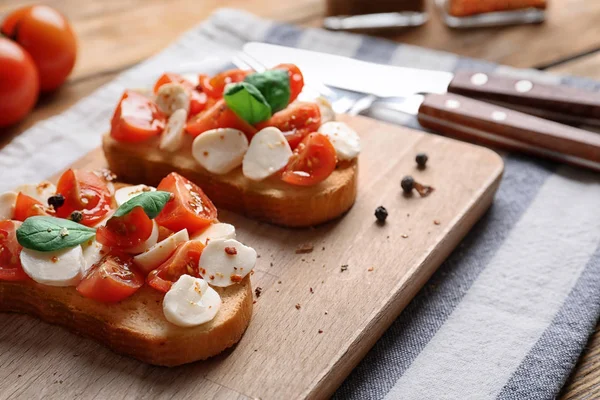 Chutné bruschetty s cherry rajčaty na dřevěné desce — Stock fotografie