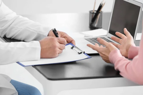 Médico masculino preenchendo formulário de candidatura enquanto consulta paciente na clínica, close-up — Fotografia de Stock