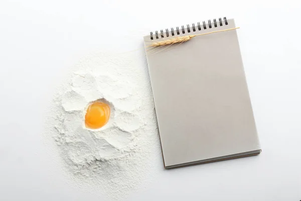 Harina con huevo para pan y cuaderno sobre fondo blanco — Foto de Stock