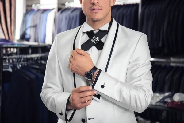 Молодой человек в элегантном костюме в магазине мужской одежды — стоковое фото