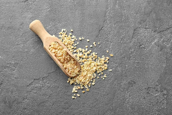 Wooden scoop with granulated dried garlic on grey background — Stock Photo, Image
