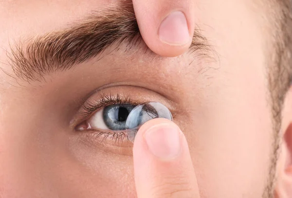Mladý muž uvedení kontaktní čočky v očích, closeup — Stock fotografie