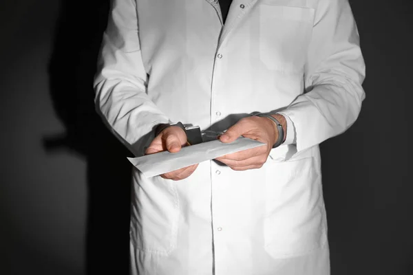 Male doctor in handcuffs holding bribe on black background — Stock Photo, Image