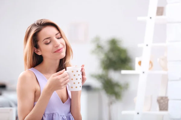 Krásná mladá žena s šálkem čaje v pohodlí domova — Stock fotografie
