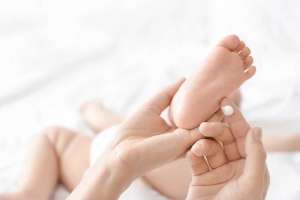 Mujer aplicando crema corporal en su bebé en casa — Foto de Stock