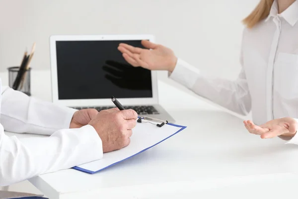 Médico masculino preenchendo formulário de candidatura enquanto consulta paciente na clínica, close-up — Fotografia de Stock