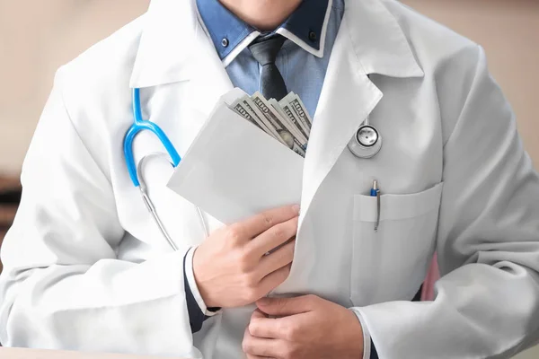 Doctor putting envelope with money in pocket, closeup. Corruption concept — Stock Photo, Image