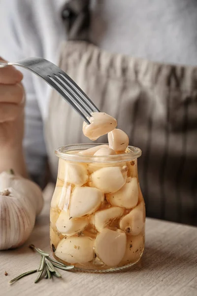 Woman trying preserved garlic on table, closeup — Stock Photo, Image