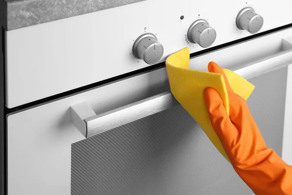 Housewife cleaning oven in kitchen — Stock Photo, Image