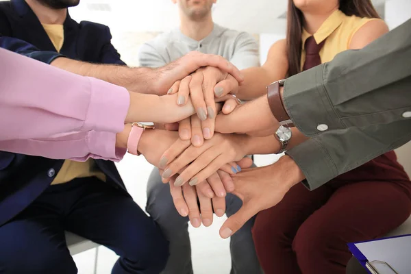 Молоді співробітники збирають руки як символ єдності, крупним планом — стокове фото