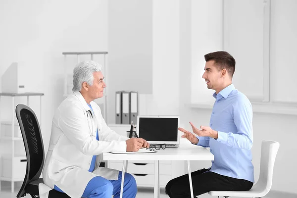 Male doctor consulting patient in clinic — Stock Photo, Image