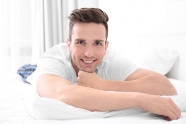 Evde beyaz yastık üzerinde yatan genç adam