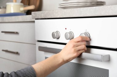 Genç kadın mutfakta modern elektrikli fırın geçiş