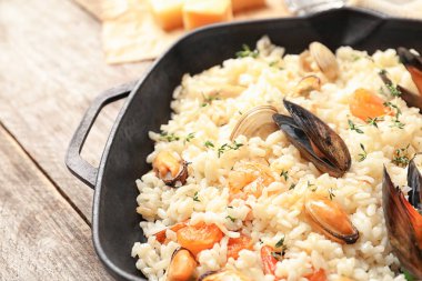 Ahşap masa üzerinde lezzetli deniz ürünleri risotto ile kızartma tavası