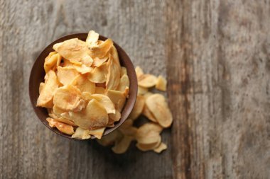 Ahşap arka plan üzerinde kuru sarımsak gevreği ile kase