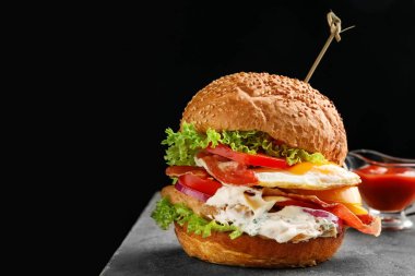 Siyah arka plan karşı tablo kızarmış yumurta ile lezzetli burger