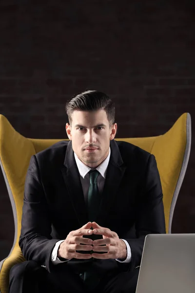 Handsome young man in stylish suit sitting in armchair indoors — Stock Photo, Image