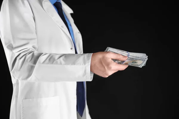 黒い背景に賄賂を保持している男性医師 — ストック写真