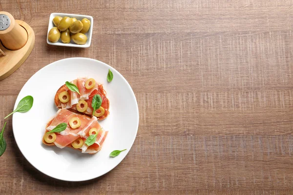 Bruschettas saborosas com azeitonas e prosciutto na placa — Fotografia de Stock