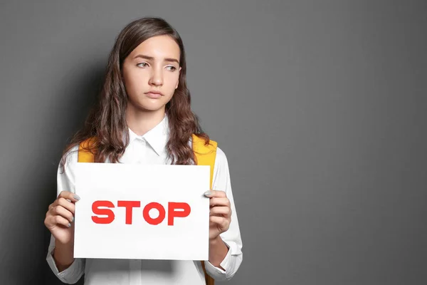 灰色の背景に単語と記号"Stop"を保持している 10 代の少女 — ストック写真