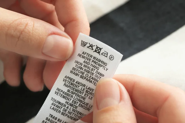 Wanita membaca instruksi pada label pakaian, closeup — Stok Foto